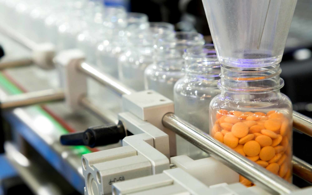 Close up view of orange pills being sorted into bottle Close up view of orange pills being sorted into bottle